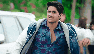 a man wearing a denim jacket and a floral shirt is making a face