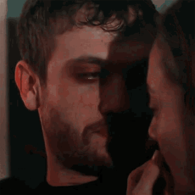a man and a woman are looking into each other 's eyes in a dark room .