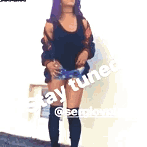 a woman with purple hair and shorts is standing on a sidewalk .