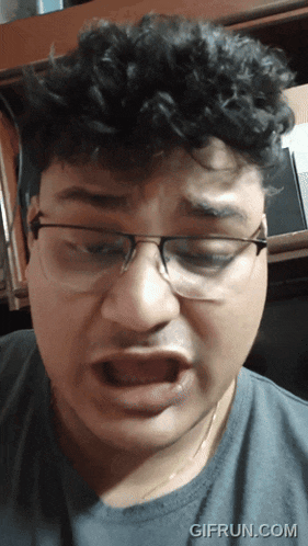 a man wearing glasses making a funny face with gifrun.com in the corner