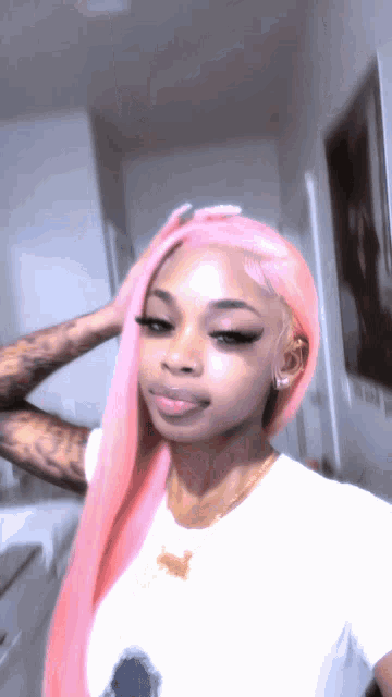 a woman with pink hair is wearing a white t-shirt and a gold necklace