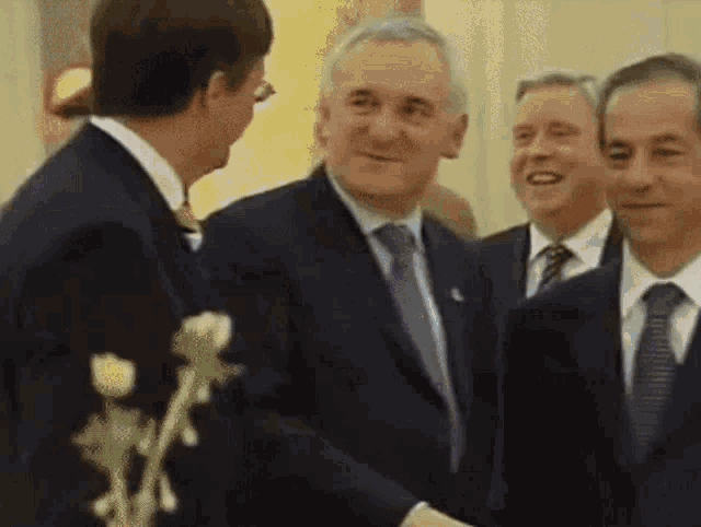 a man in a suit shakes hands with another man in a suit and tie
