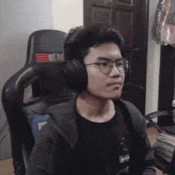 a man wearing headphones and glasses is sitting in a chair that says red label on it