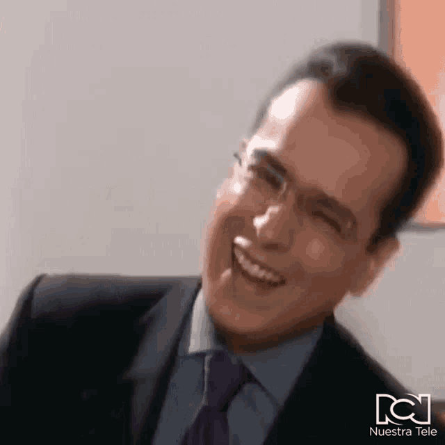 a man in a suit and tie is laughing and smiling .