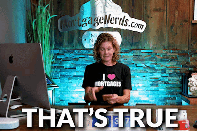 a woman wearing a shirt that says i love mortgages stands in front of an apple computer