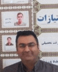 a man wearing glasses is standing in front of a wall with arabic writing .