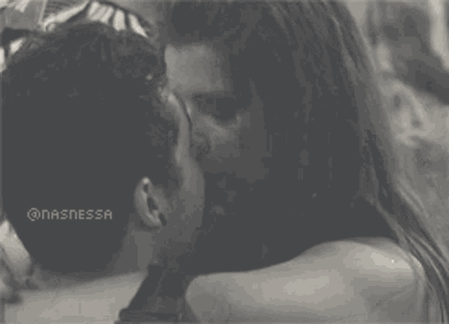 a black and white photo of a man and woman kissing with nasnessa written on the bottom