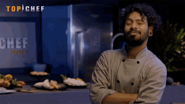 a chef stands with his arms crossed in front of a top chef sign