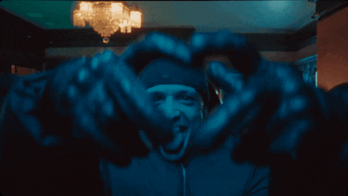 a man sticking his tongue out in a dark room with a chandelier hanging from the ceiling
