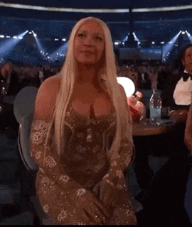 a woman in a gold dress is sitting in front of a crowd at a concert .