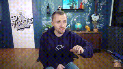 a man in a purple hoodie is sitting in a chair in a room with a chalkboard wall .