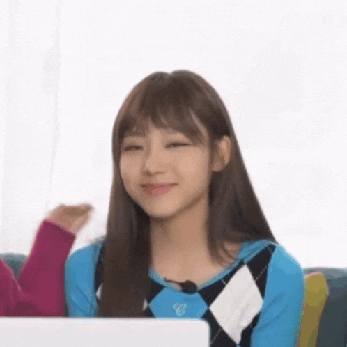 a girl is sitting on a couch with a laptop and smiling .