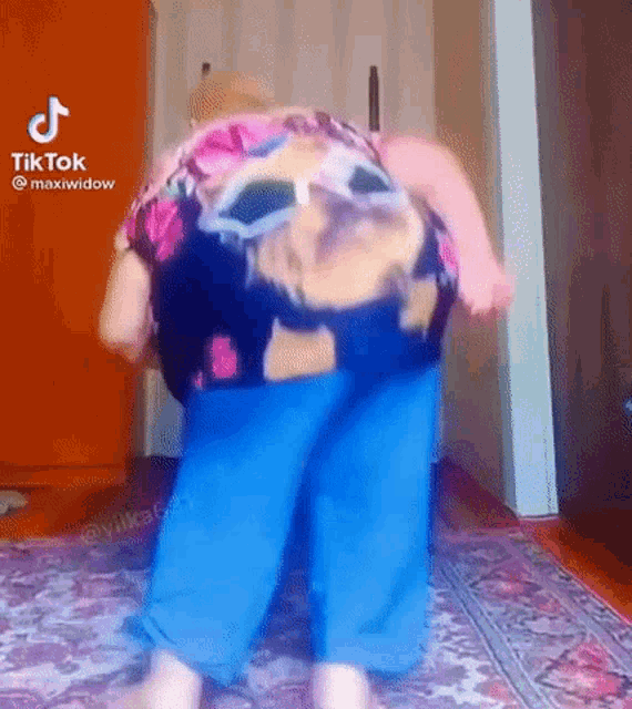 an older woman is dancing on a rug in a room .