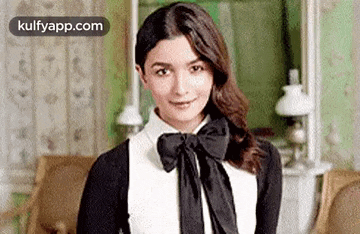 a woman wearing a black and white shirt with a bow tie is standing in a room .