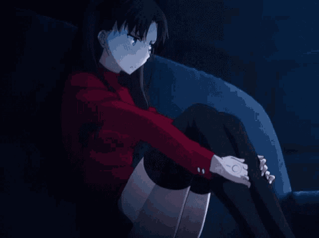 a girl in a red shirt sits on a couch