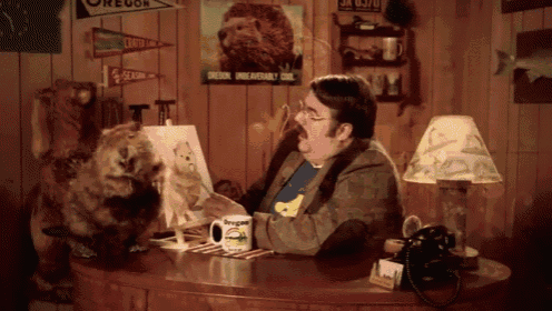 a man is sitting at a desk with a mug that says oregon on it