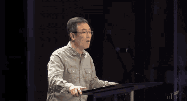 a man stands at a podium with a phone screen showing a 58 %