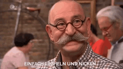 a man with a mustache and glasses is laughing and saying einfach lacheln und nicken .
