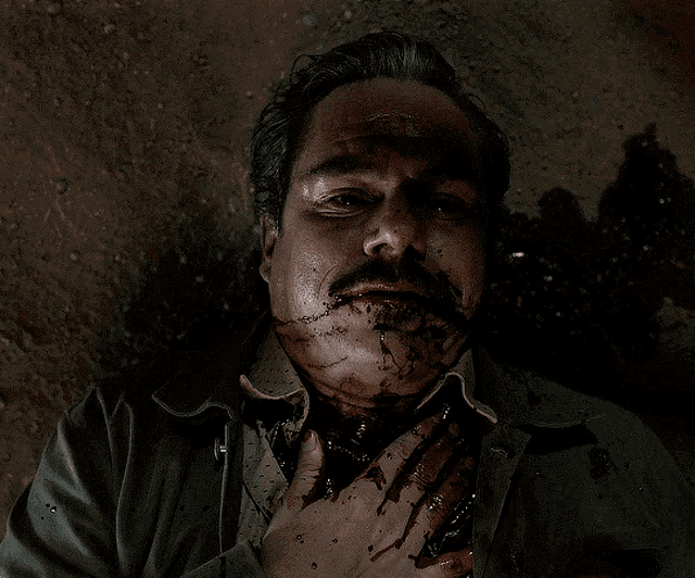 a man with blood on his face is smiling with his mouth open