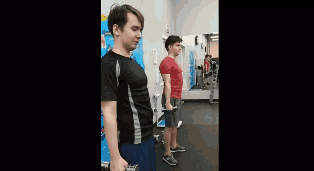 two men are holding dumbbells in a gym .