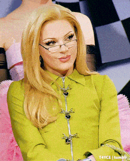 a woman wearing glasses and a green shirt is sitting on a pink couch