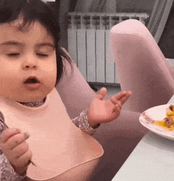 a baby wearing a bib is sitting at a table eating food