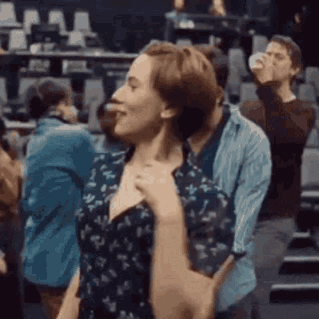 a woman is dancing with a man in a crowd of people in a theater .