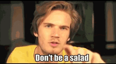 a man in a yellow shirt is pointing at the camera and saying `` don t be a salad '' .