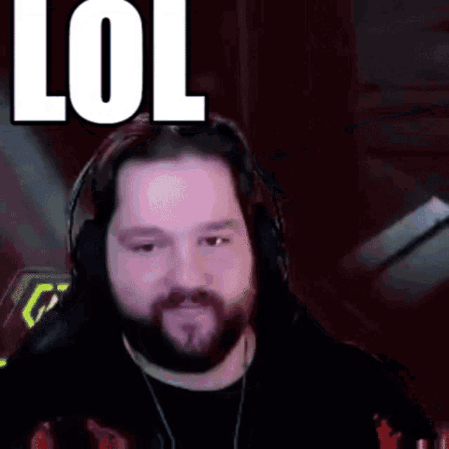 a man with a beard is wearing headphones and making a funny face while looking at the camera .