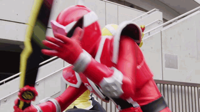 a man in a red superhero costume is holding a yellow sword .