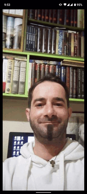 a man with a beard is smiling in front of a bookshelf with a book called spider-man