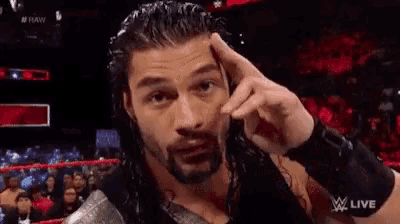roman reigns is wearing a black tank top and holding a hammer in his hand .