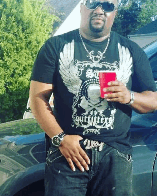 a man wearing a outfitters t-shirt holds a red cup