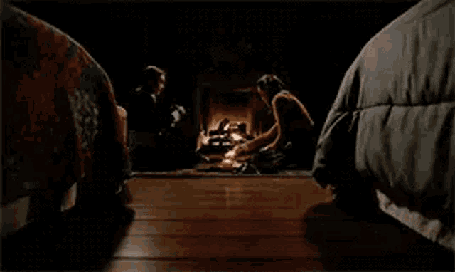 a group of people are sitting around a fire in a dark room .