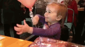 a little girl in a purple shirt is holding a balloon in her hand