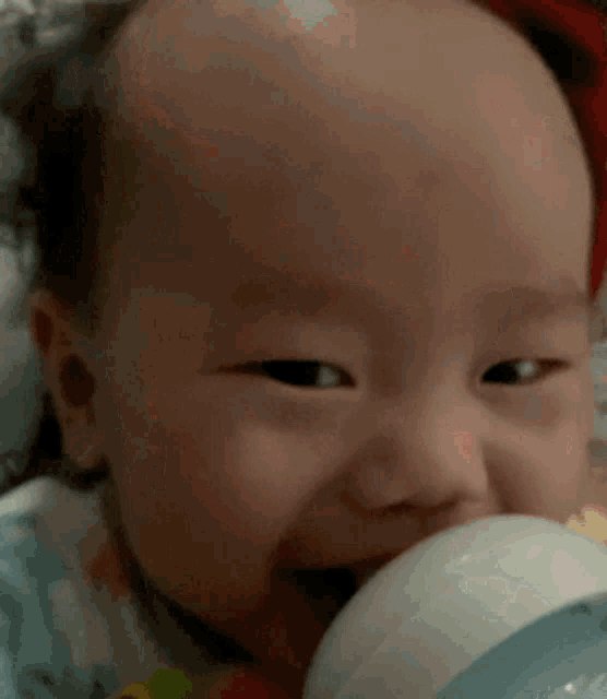 a baby is drinking from a bottle and making a face