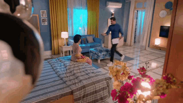 a man is running towards a woman sitting on a bed in a living room .