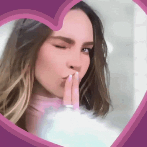 a woman blowing a kiss behind a pink heart