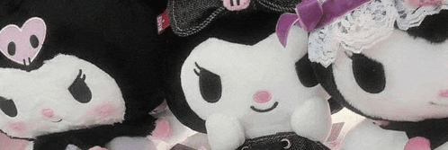 three stuffed kuromi dolls are sitting next to each other .