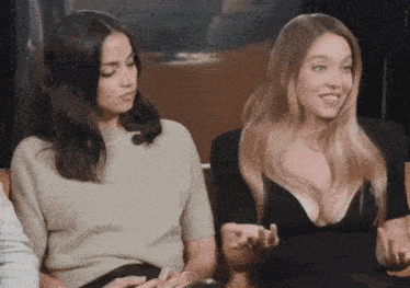 two women sitting next to each other with one wearing a black dress