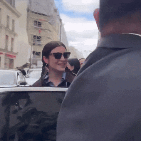a woman wearing sunglasses is talking to a man in a car