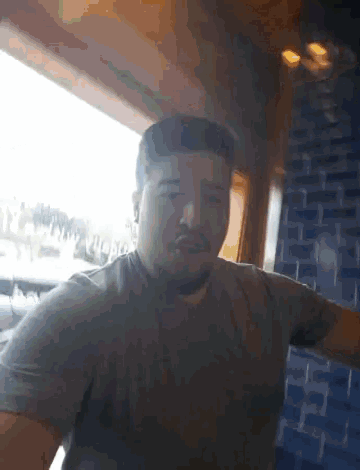 a man with a beard is sitting in front of a window in a restaurant