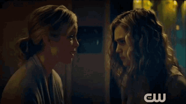 two women looking at each other with a cw logo in the corner