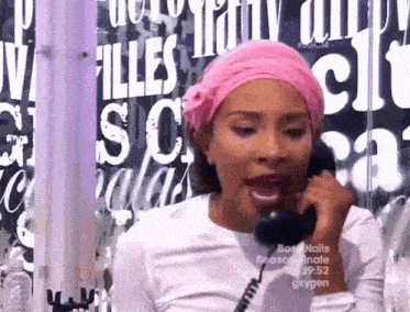 a woman wearing a pink headband is talking on a phone in front of a sign that says oxygen
