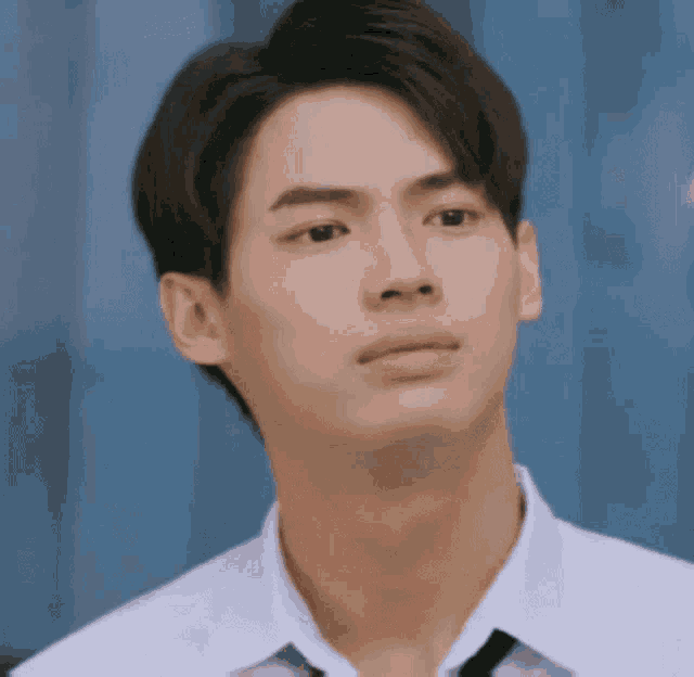 a young man in a white shirt and tie is looking at the camera .