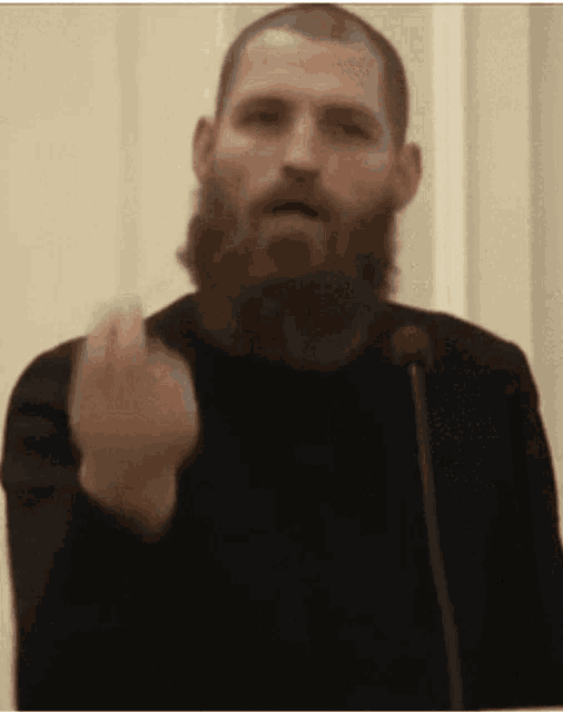 a man with a beard is giving a speech at a podium