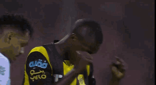 a man wearing a black and yellow jersey with the letter t on the front