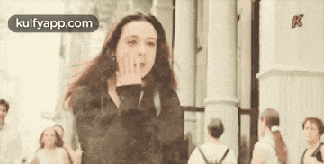 a woman is blowing a kiss in front of a crowd of people on a city street .