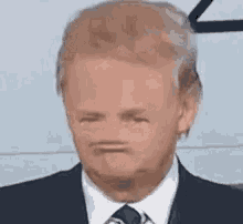 a man in a suit and tie is making a funny face with his mouth open .