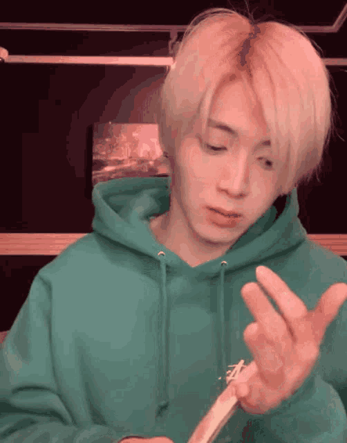 a man in a green hoodie is holding something in his hands